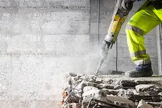 Worker using jackhammer to break concrete, representing systemic attacks on people doing good work in public service
